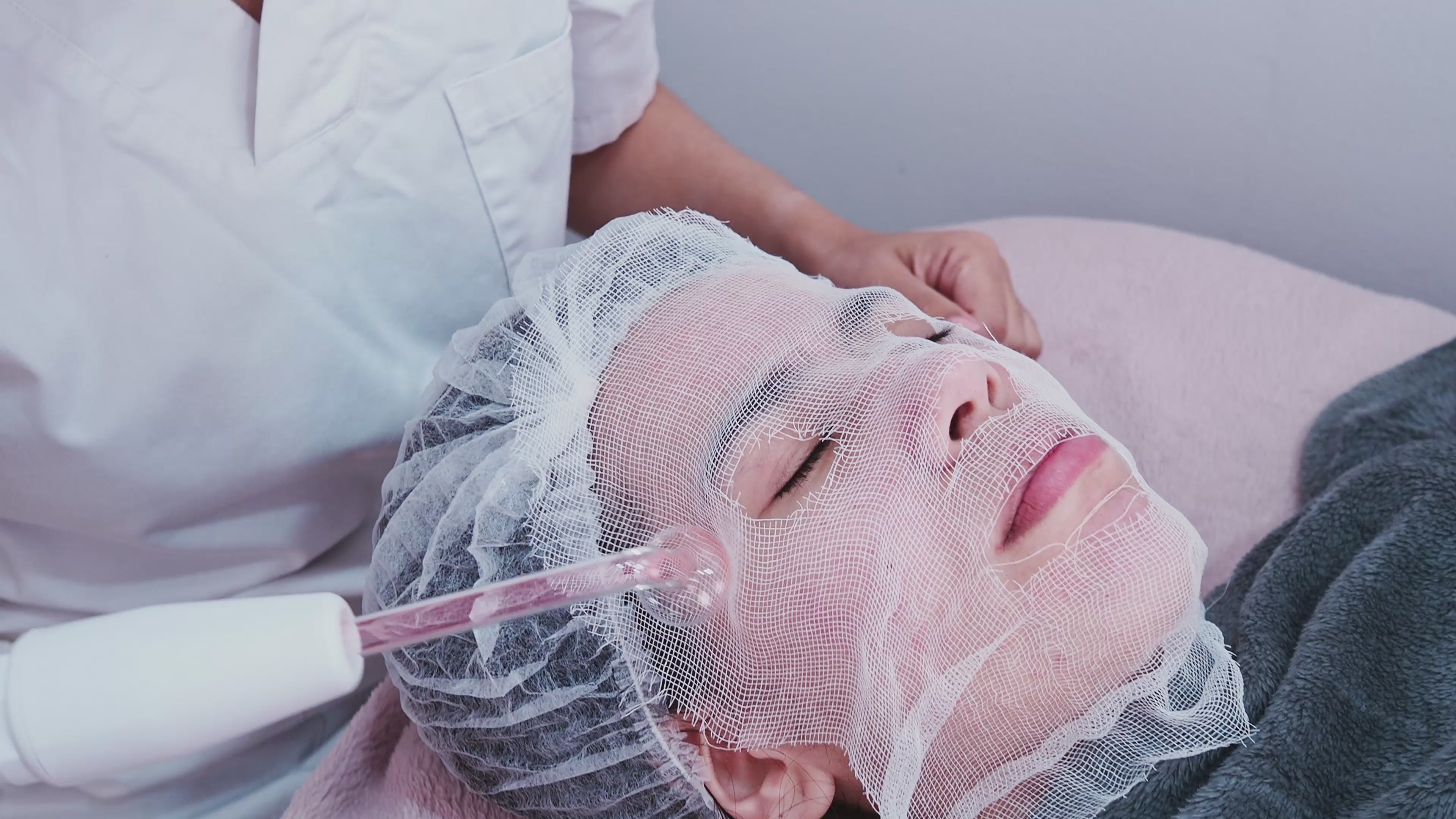 Load video: a video of a woman with a face net getting professional treatment with acne frequency wand